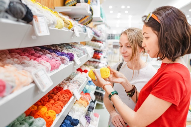 Shelf at craft store, with ribbons and women are shopping